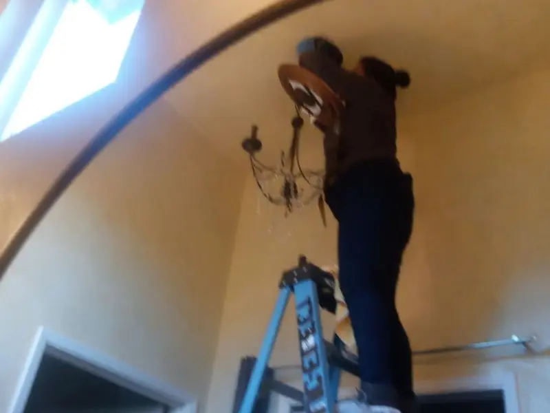 Electrician installing a chandelier in a Mancelona residence